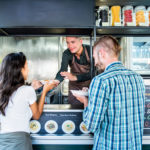 Couple buying pasta from food truck at outdoor market
