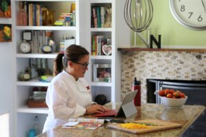 Female online culinary student working on her computer in the kitchen