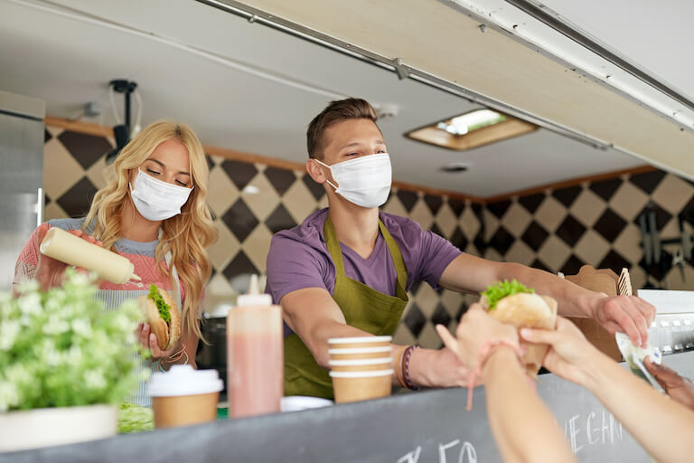 Food truck employees wearing masks handing food to customers
