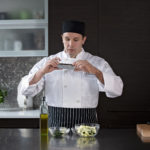 Male culinary student taking photo of seasoning and cut vegetables