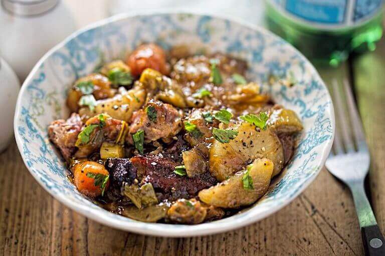 Slow roasted lamb with carrots in a blue and white bowl 