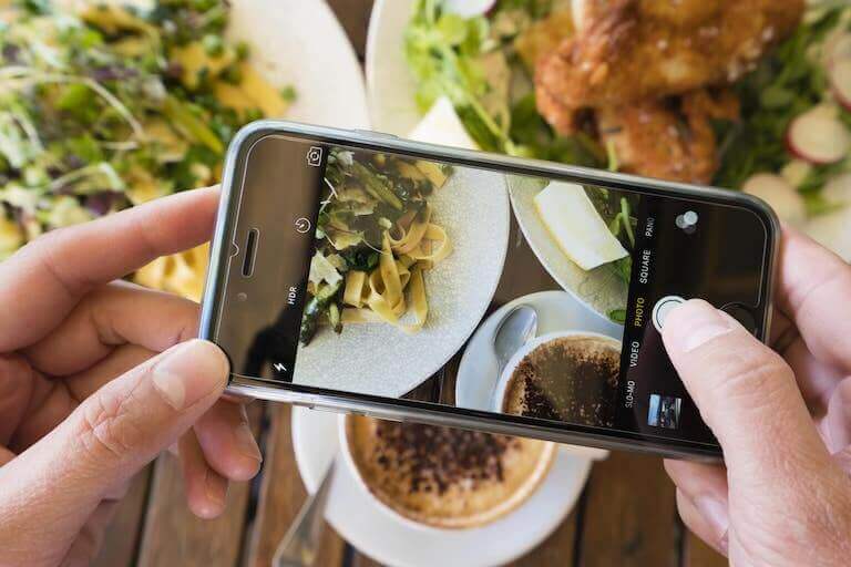 Taking photo with phone of plated pasta and dessert dish