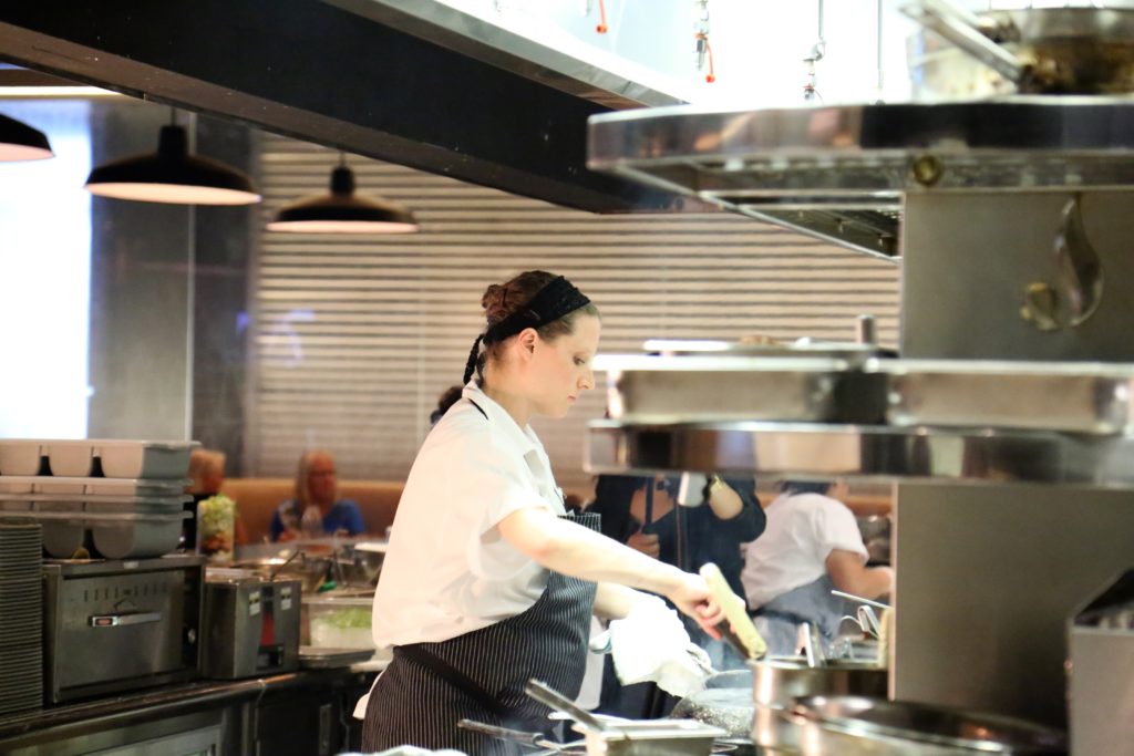 Female cook stirring a dish in a commercial kitchen