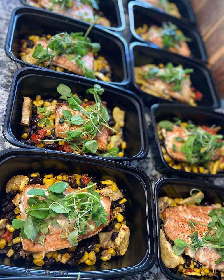 Salmon with corn and beans in black to go containers