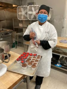 Pastry arts student decorating Escoffier Day cupcakes