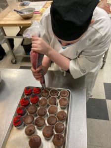 Pastry arts student icing chocolate cupcakes