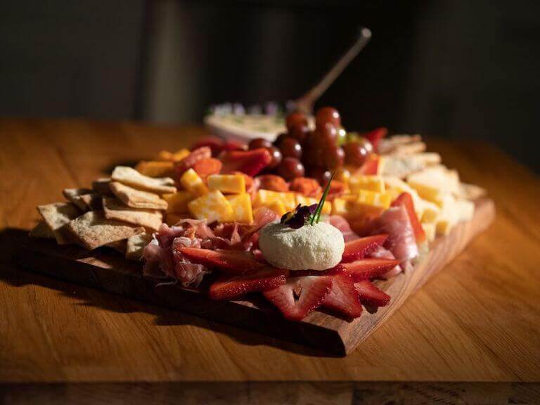 Charcuterie Board with strawberries, grapes, crackers, and a variety of cheese and meats