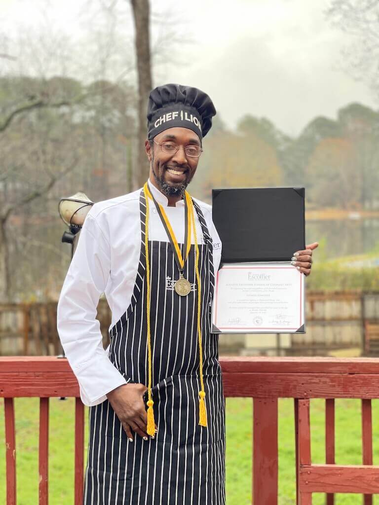 Escoffier graduate posing in uniform with diploma