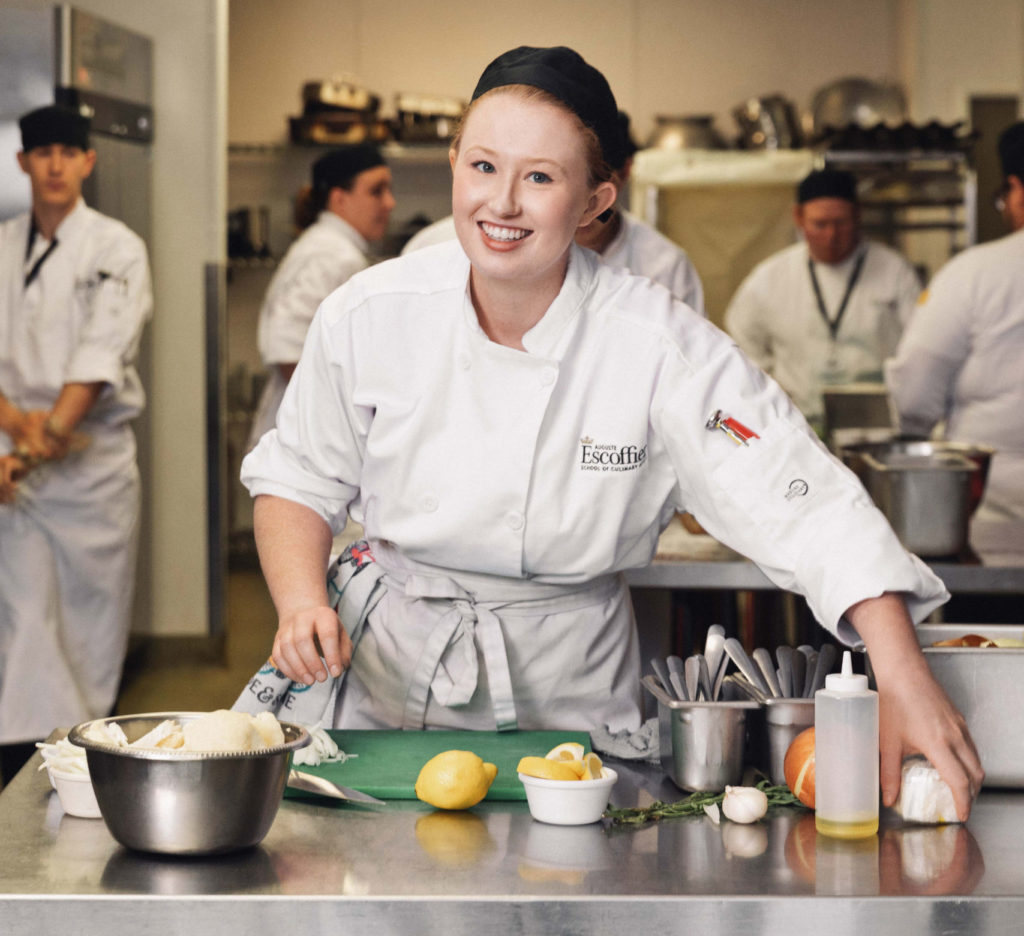 Smiling female culinary student cutting lemons