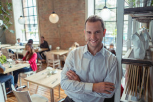 Smiling male manager in dress shirt in cafe