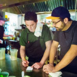 Two male cooks looking at a receipt order in a commercial kitchen