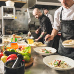 A cook in an apron makes a salad of vegetables and pizza