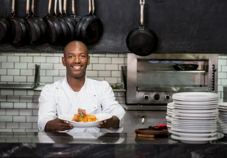 Chef working in a kitchen and showing his plate