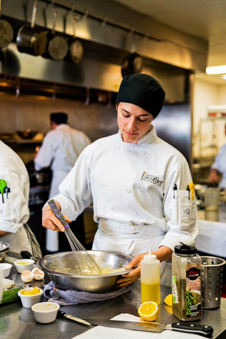 Female Escoffier student mixing and whisking a bowl