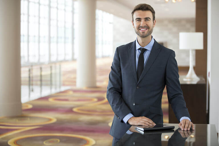 Hotel manager standing next to a desk in the lobby 