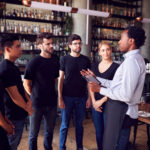 Male Restaurant Manager With Digital Tablet Giving Team Talk To Waiting Staff