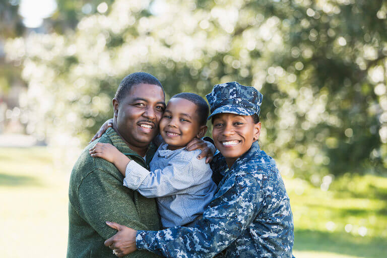 Military woman hugging her husband and son