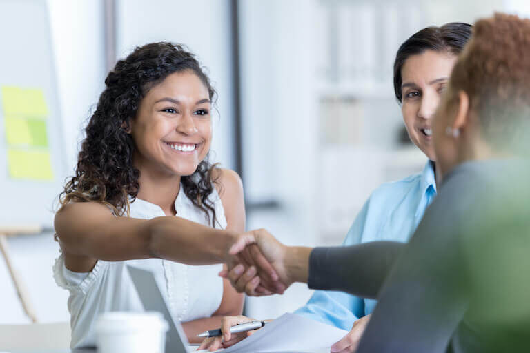 Smiling woman shaking hands with another woman in business deal