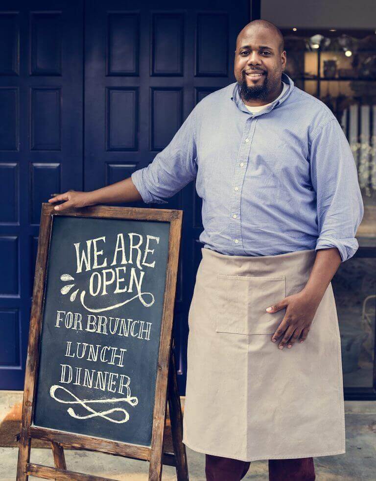 A cheerful business owner standing with an open sign