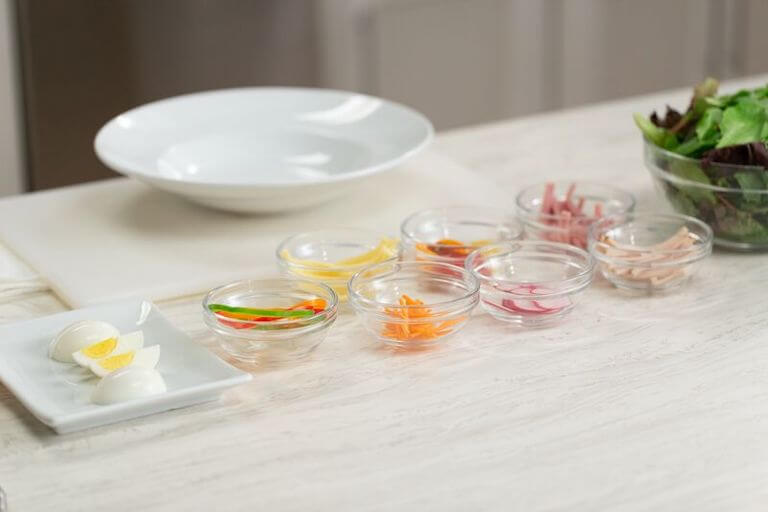 Boiled eggs, carrots, lettuce, and other ingredients for a salad separated into small glass bowls