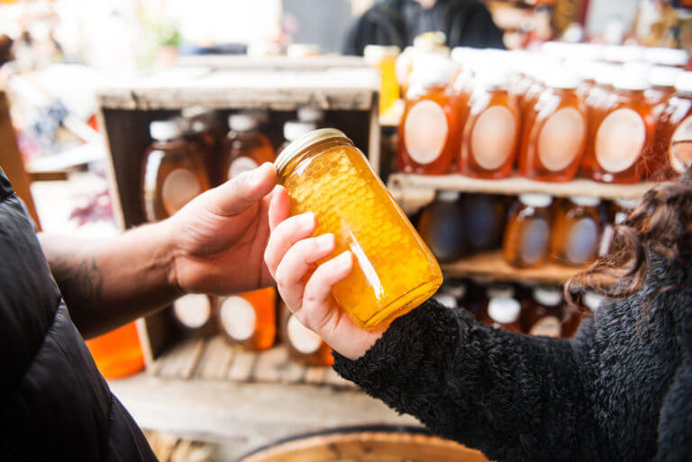 Employee handing a customer a jar of fresh honey