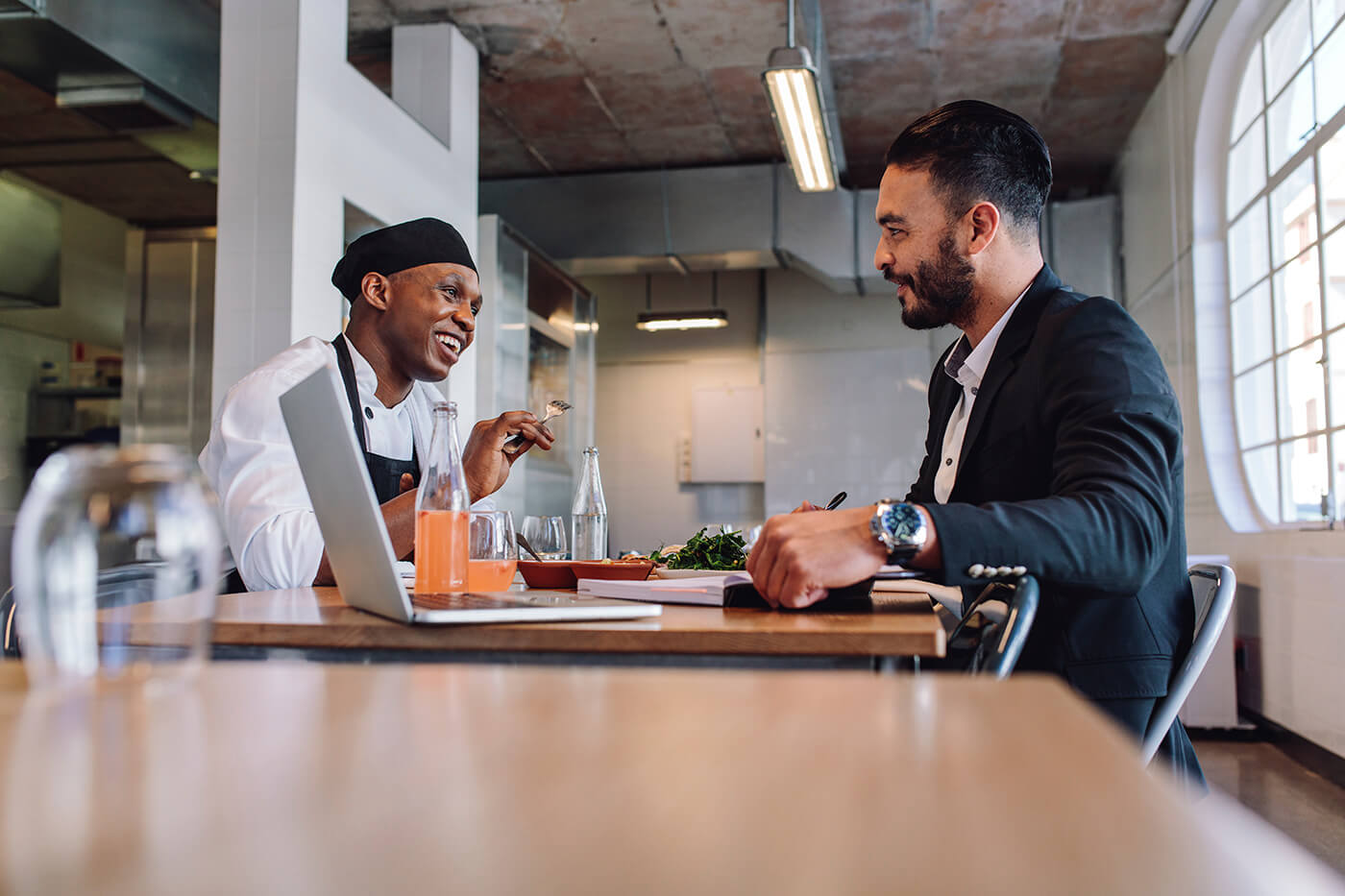 Restaurant manager having a conversation with chef with laptop on table