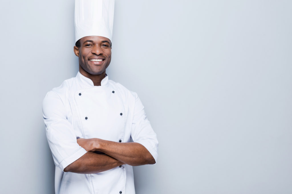 Smiling male black chef with white coat and hat