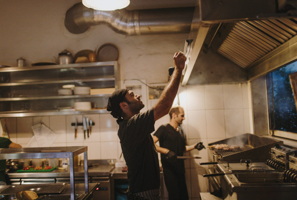 Two chefs wearing black working in the grill cooking meat