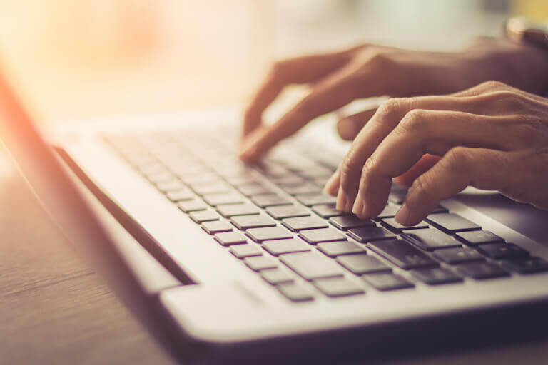 Close up of hands typing on the keyboard of a laptop
