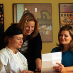 Two women financial aid advisors going over paper with female escoffier student in uniform