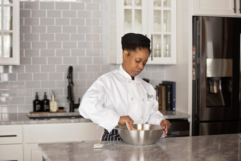 Culinary student mixing dough in a large silver bowl