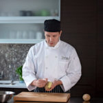Escoffier online student peeling a potato with a peeler in home kitchen