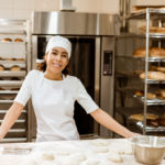 Female baker in a bakery making bread from dough