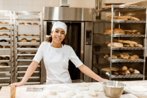 Female baker in a bakery making bread from dough