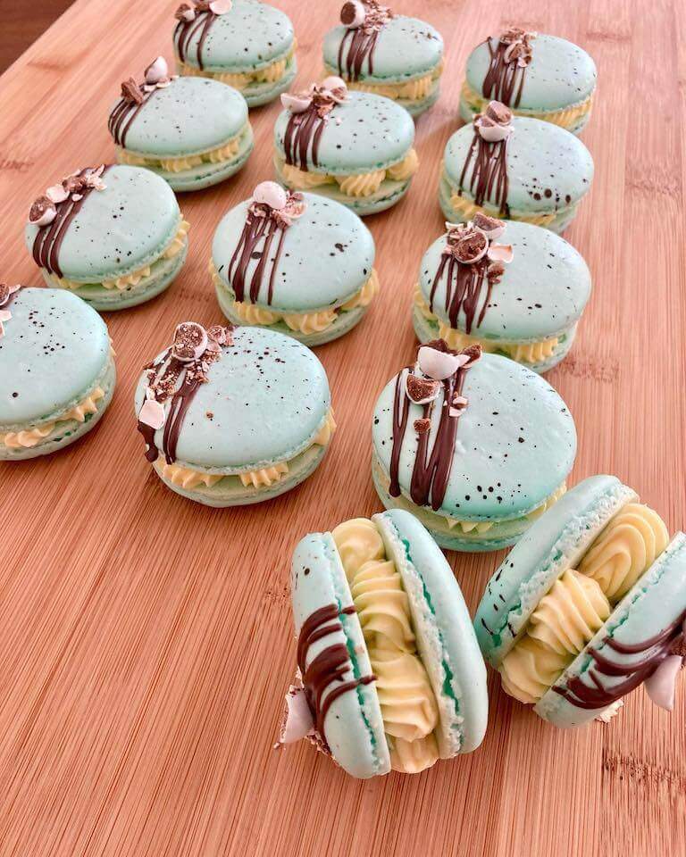 Light blue macarons decorated with chocolate on a wooden table