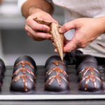 Pastry chef using a piping decorating tube to make chocolate decorations