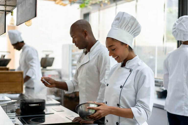 Two chefs working over the stove preparing food