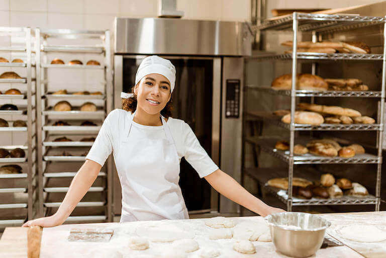 baker standing at a table with fresh dough in a bakery