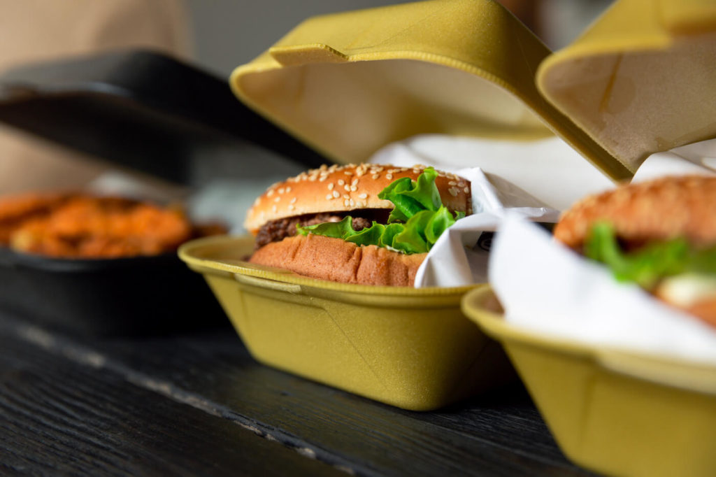 Hamburger in a takeaway container on the wooden background