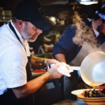 Escoffier Online graduate & Executive Chef/Owner Lance McWhorter pouring broth over a mussels dish