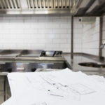 Commercial kitchen with white design papers in front of sink