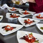 Cook plating white dishes with tomatoes and feta cheese