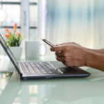Man using black laptop computer and phone