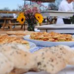Mini sandwiches and bread on a plate in front of flowers