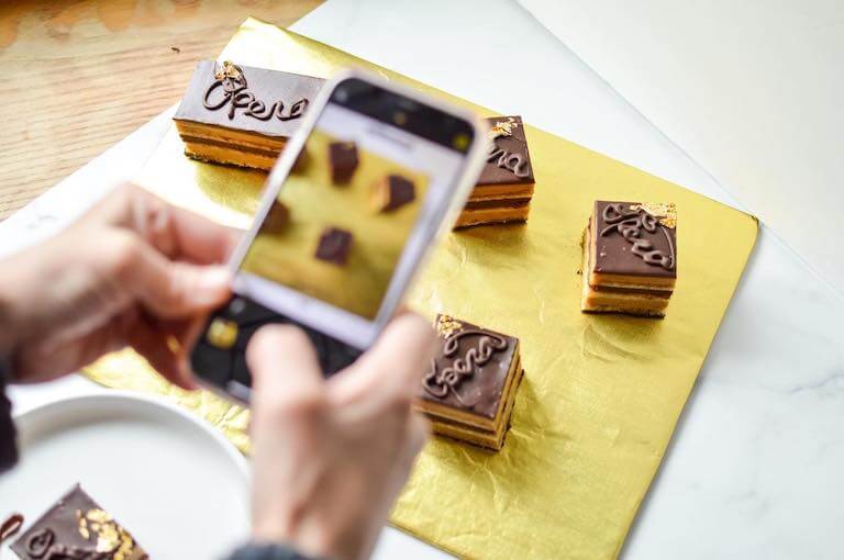 Small square cakes with chocolate frosting and Opera written on them