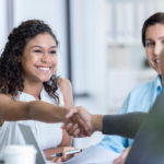 Smiling woman shaking hands with another woman in business deal