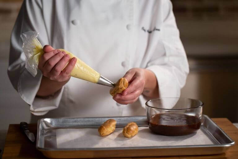 Chef filling eclairs with pastry cream
