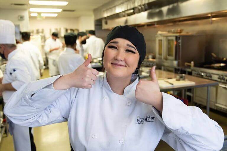 Escoffier student posing with two thumbs up for a picture