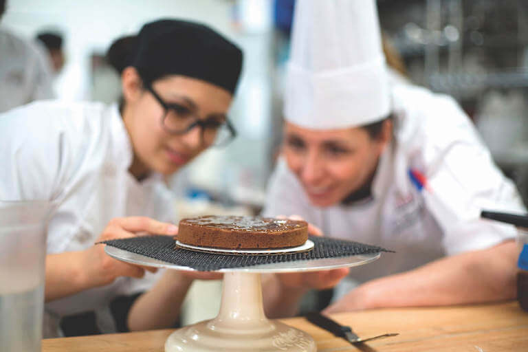 Pastry students looking at baked chocolate dessert