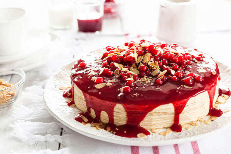 Dessert cake with red sauce, cherries, and sliced almonds